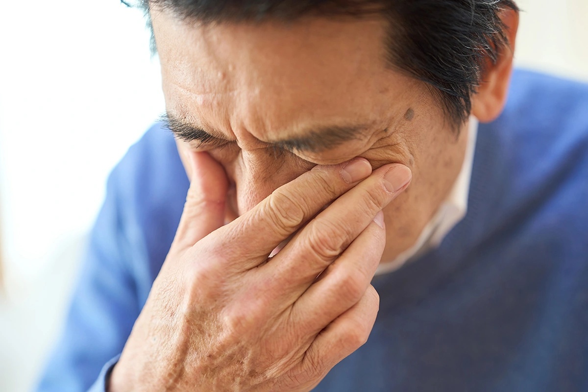 Man rubbing his eye due to discomfort and irritation caused by a corneal infection. 